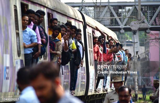 Commuters from a running local train watch railway engineers move a derailed coach from the railway tracks after three coaches of 11005...