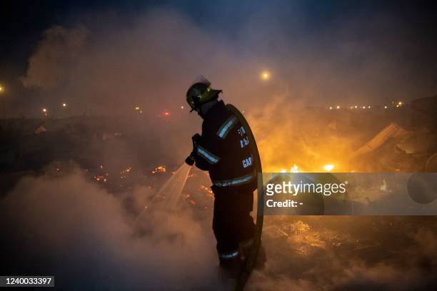 Members of the City of Cape Town Fire and Rescue Services extinguish a fire after it broke out in the Joe Slovo Informal Settlement in Langa, one of...