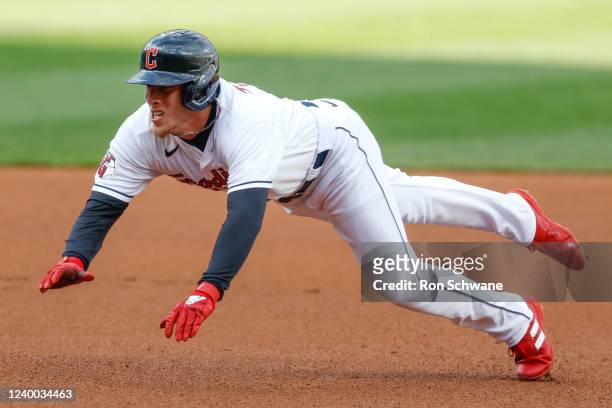 Myles Straw of the Cleveland Guardians dives safely into third base with a triple against the San Francisco Giants during the first inning at...