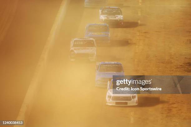 Cloud of dust fills the air as trucks pull onto pit road during the NASCAR Camping World Truck Series Pinty's Truck Race on Dirt on April 16, 2022 at...
