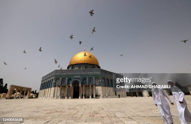 Palestinian Muslims walk in front of the Dome of Rock mosque at the Al-Aqsa mosque compound in Jerusalem's Old City on April 17, 2022. - More than 20...