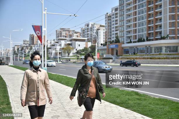 People walk on a street in the newly built residential area of Kyongru-Dong, in the Central District of Pyongyang on April 17, 2022.