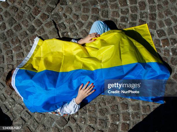 Ukrainian woman with the Ukrainian flag lie on the ground in front of the Dam square in Amsterdam, to protest Russias war in Ukraine, on April 17th,...