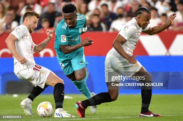 Real Madrid's Brazilian forward Vinicius Junior vies with Sevilla's Croatian midfielder Ivan Rakitic and Sevilla's French defender Jules Kounde...