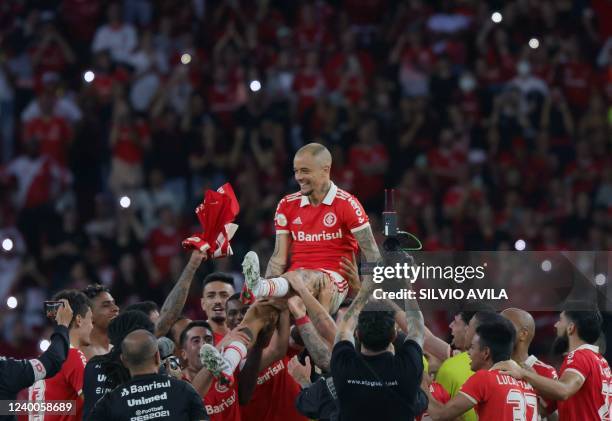 Brazil's Internacional Argentine attacking midfielder Andres D'Alessandro is lifted by teammates at the end of his last match as professional...