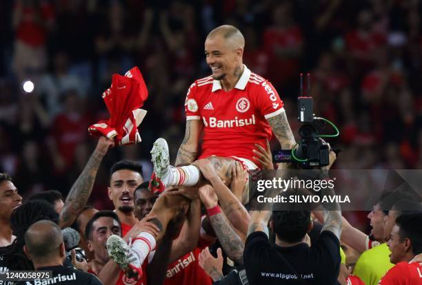 Brazil's Internacional Argentine attacking midfielder Andres D'Alessandro is lifted by teammates at the end of his last match as professional...