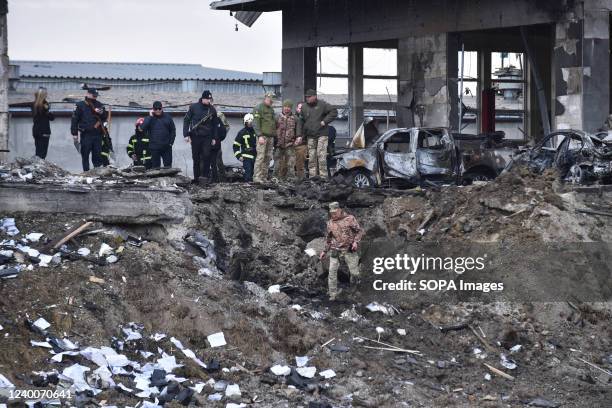 Soldiers inspect the crash site of a Russian missile that hit a car service station in Lviv after the morning shelling of the city by Russian...