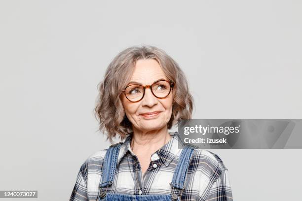 porträt einer fröhlichen seniorin, die kariertes hemd trägt - mature woman portrait studio stock-fotos und bilder