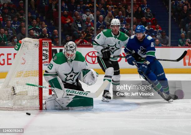 Jason Dickinson of the Vancouver Canucks looks on as Jake Oettinger of the Dallas Stars makes a save during their NHL game at Rogers Arena April 18,...