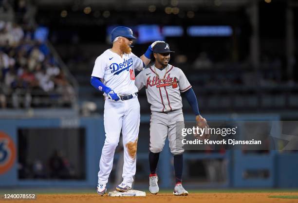 Justin Turner of the Los Angeles Dodgers is greeted by Ozzie Albies of the Atlanta Braves after hitting a double during the fourth inning against...