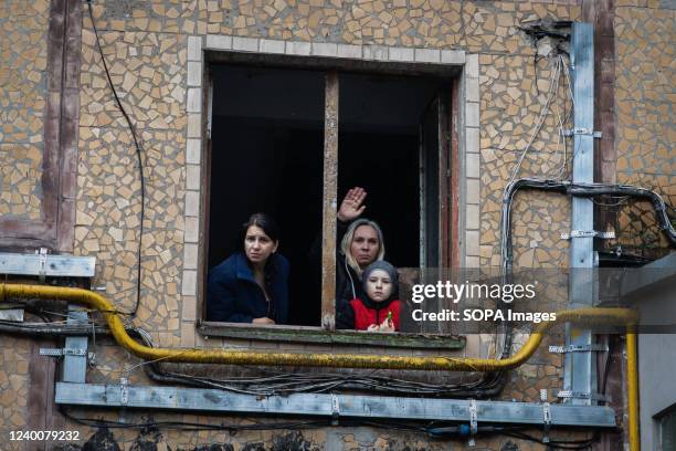 Woman waves through the apartment window after a Ukrainian firefighter inquired about their safety following a Russian missile attack on the city....