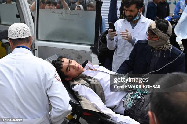 Medical staff move a wounded youth on a stretcher outside a hospital in Kabul on April 19 in Kabul on April 19 after two bomb blasts rocked a boys'...