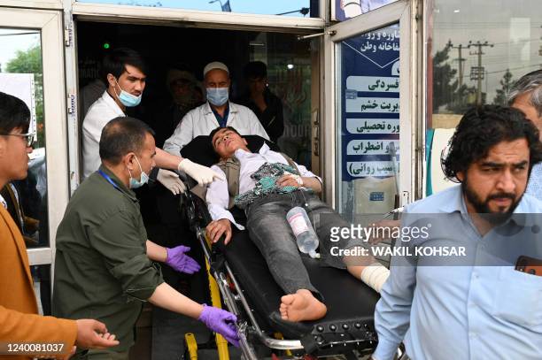 Medical staff move a wounded youth on a stretcher inside a hospital in Kabul on April 19 in Kabul on April 19 after two bomb blasts rocked a boys'...