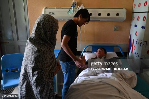 Relatives visit a wounded youth at a hospital in Kabul on April 19 after two bomb blasts rocked a boys' school in a Shiite Hazara neighbourhood...