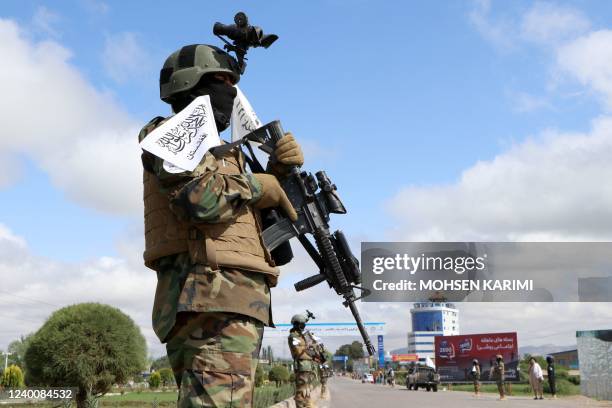 Member of the Taliban stand guard along a road from where other Taliban fighters are to arrive in a military street parade in Herat on April 19, 2022.