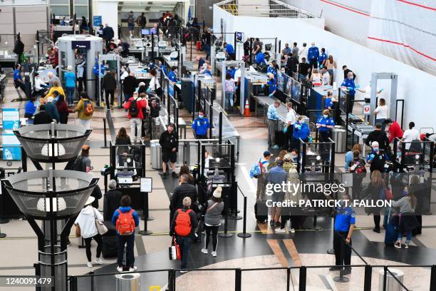 Airline passengers, some not wearing face masks following the end of Covid-19 public transportation rules, wait at a Transportation Security...