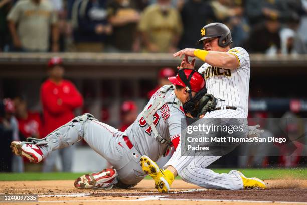 Luke Voit of the San Diego Padres crashes into Tyler Stephenson of the Cincinnati Reds in the first inning at Petco Park on April 19, 2022 in San...