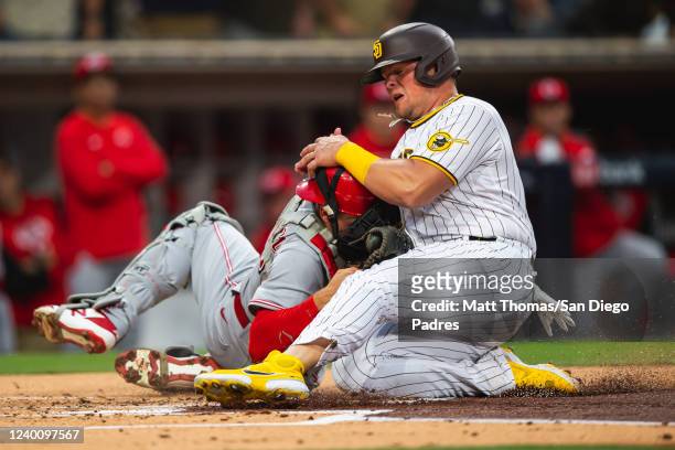 Luke Voit of the San Diego Padres crashes into Tyler Stephenson of the Cincinnati Reds in the first inning at Petco Park on April 19, 2022 in San...