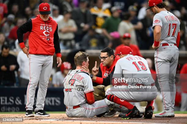 Tyler Stephenson of the Cincinnati Reds is checked by a trainer after a collision at the plate during the second inning of a baseball game against...