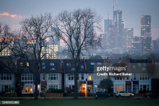 Through a gap of 100 year-old ash trees are Edwardian period homes bordering Ruskin Park in south London with residential high-rises at the distant...