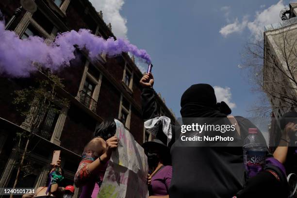 Members of a feminist collective in Mexico City set off a purple flare in front of police officers during a march against male violence and the...