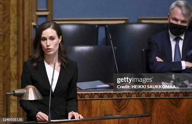 Finnish Prime Minister Sanna Marin speaks while Foreign Minister Pekka Haavisto listens during a plenary session at the Finnish Parliament in...