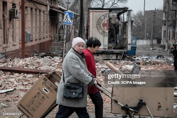 Residents drag supplies past a bombed out Red Cross humanitarian aid truck in a devastated area of central Mariupol. The battle between Russian / Pro...