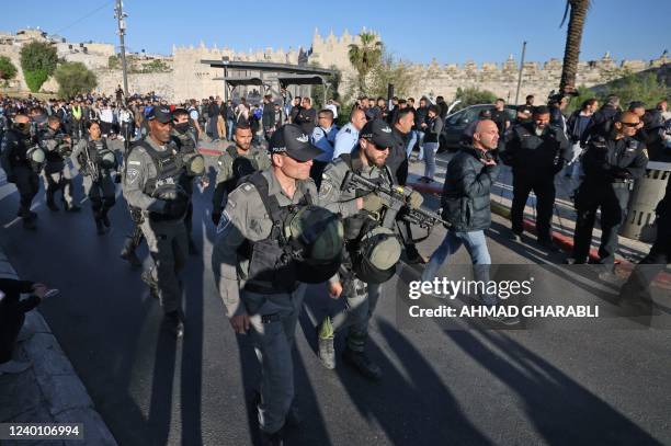 Israeli security forces keep Palestinians at bay in front of the Damascus Gate in Jerusalem's Old City, as they gather to watch Israeli protesters...