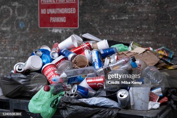 Overflowing commercial rubbish bin full of plastic drinks bottles and metal cans on 11th April 2022 in London, United Kingdom.