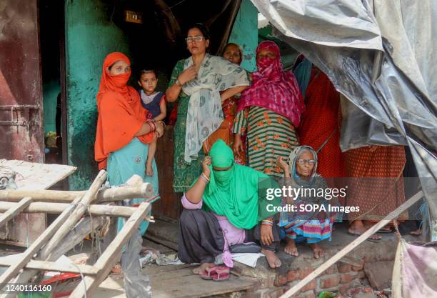 Local residents stand inside a house after a bulldozer demolished an illegal structure during a joint anti-encroachment drive conducted by North...