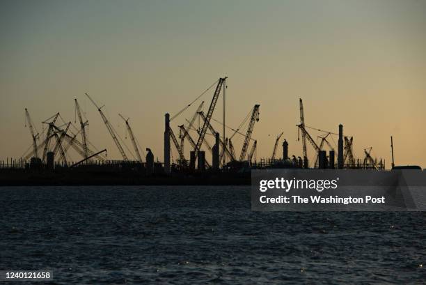 Construction cranes stand silhouetted by the sunset at the Golden Pass LNG Terminal in Sabine Pass, TX, on Thursday, April 14, 2022. Golden Pass LNG,...