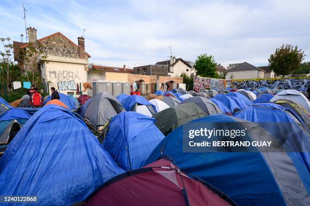 Asylum seekers, mainly from Afghanistan, stand by their tents at a makeshift migrant camp in Pantin, northeastern suburbs of Paris, on April 20, 2022.