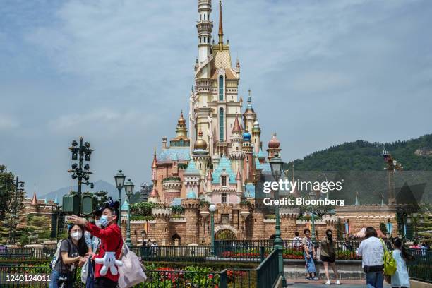 Visitors wearing protective masks take pictures in front of the Castle of Magical Dreams at Walt Disney Co.'s Disneyland Resort during its reopening...