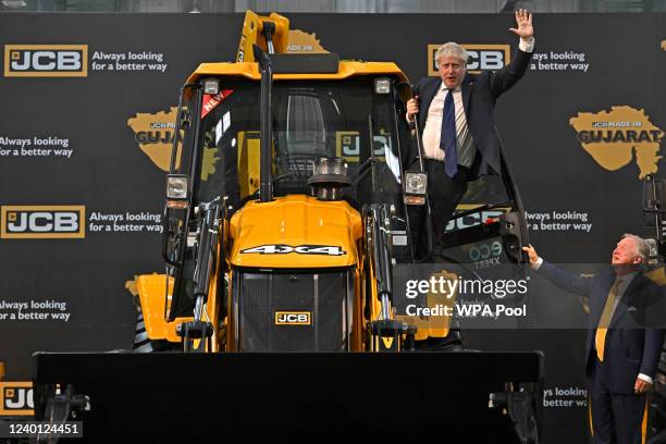 Prime Minister Boris Johnson waves from an excavator as JCB chairman Lord Bamford watches at the new JCB Factory in Vadodara, Gujarat, during his two...