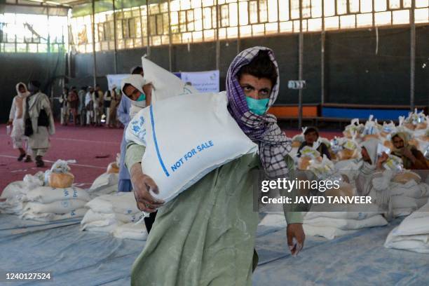 An Afghan man carries sacks of grains he received at a World Food Programme facility as an aid to Afghan people with children suffering from...