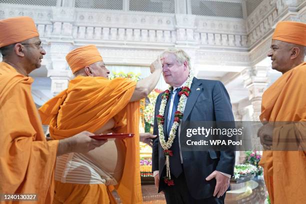 Prime minister Boris Johnson has a tilak applied to his forehead by a senior sadhu as he visits the Swaminarayan Akshardham temple during his two day...