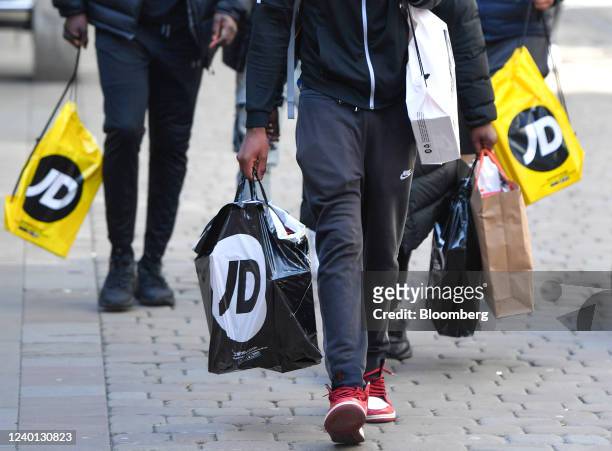 Shoppers carry bags from JD Sports Fashion Plc in Manchester, U.K., on Thursday, April 21, 2022. The Office for National Statistics are due to...