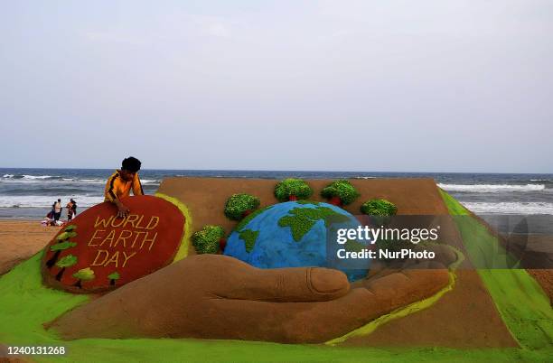 Sand artist Manas Sahoo gives his finishing touches to his sand sculpture on the eve of World Earth Day for visitors awareness at the Bay of Bengal...