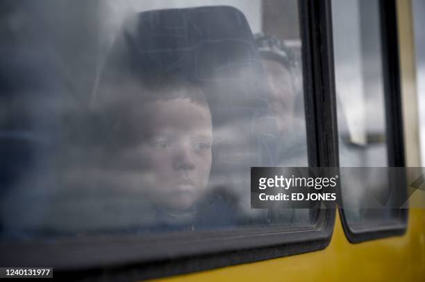 Boy looks through the window of a bus as people fleeing fighting in the southern city of Mariupol arrive in a small convoy after the opening of a...