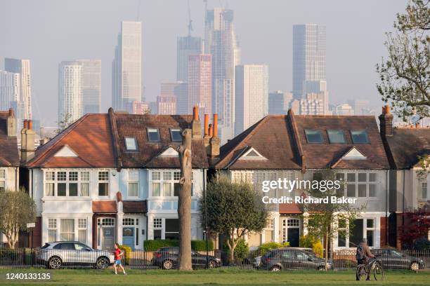 South Londoners walk in front of terraced period homes and in the distance, the growing development at Nine Elms at Battersea, seen from Ruskin Park,...