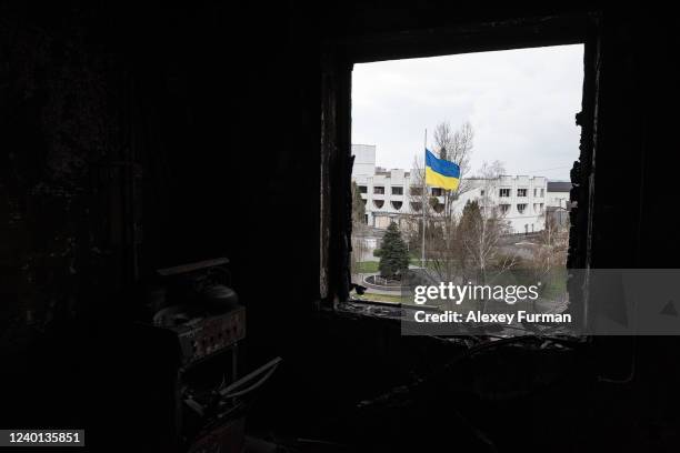 Ukrainian national flag on a pole is seen through a window of a destroyed apartment, on April 21, 2022 in Borodianka, Ukraine.