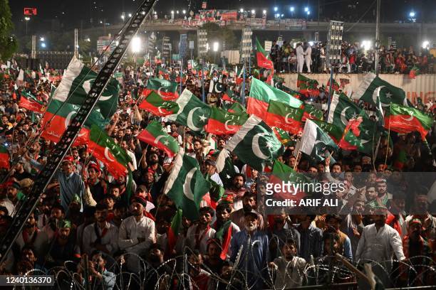 Supporters of Pakistan Tehreek-e-Insaf party, of former Pakistan's prime minister Imran Khan, hold party and Pakistani flags as they listen to speech...