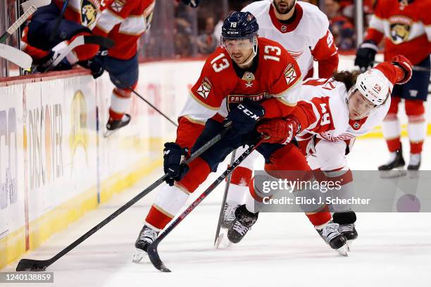 Sam Reinhart of the Florida Panthers digs the puck out from the boards against Tyler Bertuzzi of the Detroit Red Wings at the FLA Live Arena on April...