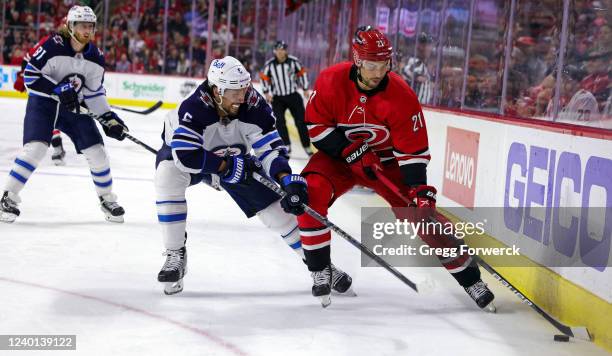 Nino Niederreiter of the Carolina Hurricanes controls the puck away from Brenden Dillon of the Winnipeg Jets during an NHL game on April 21, 2022 at...