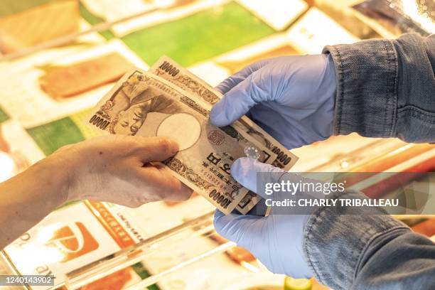 Woman pays a vendor with Japanese yen at a shop in Tokyo's Tsukiji area on April 22, 2022.