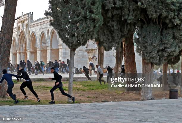 Palestinian demonstrators run in retreat during clashes with Israeli security forces inside Jerusalem's Al-Aqsa Mosque complex, early on April 22,...