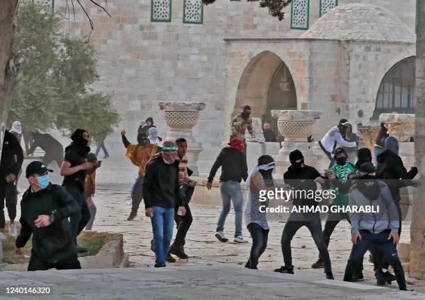Palestinian demonstrators hurl rocks during clashes with Israeli security forces inside Jerusalem's Al-Aqsa Mosque complex, early on April 22, 2022....