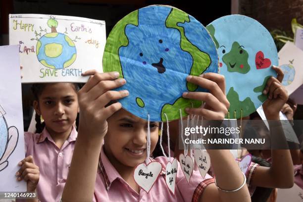 Students hold their paintings with enviromental themes as they gather on the occasion of 'Earth Day' at a school in Amritsar on April 22, 2022.