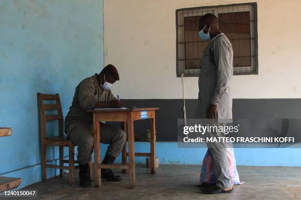 The relative of an inmate is registered by a Togolese warden at the entrance of the Lome Prison on April 22, 2022. - Togo is to allow prison visits...