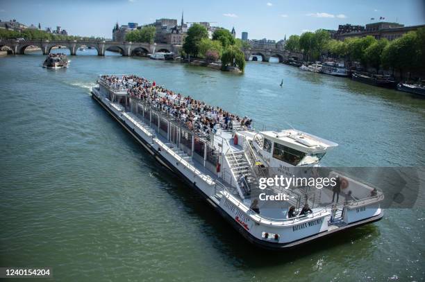 Passengers travel in a 'Bateaux Mouches' in spring sunshine on the River Seine in Paris on April 22, 2022.